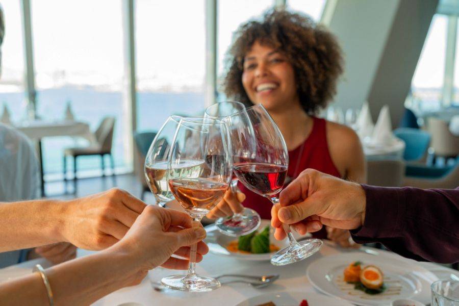 Gruppe stößt mit Weingläsern beim Abendessen auf einem Kreuzfahrtschiff an