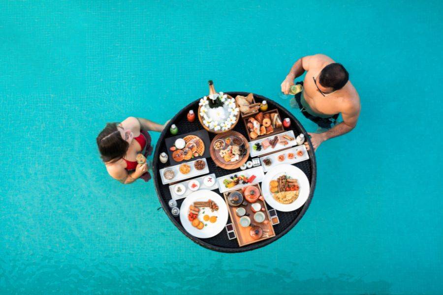 Das Floating Breakfast von oben. Eine Frau und ein Mann genießen die Mahlzeit gemeinsam im Pool.