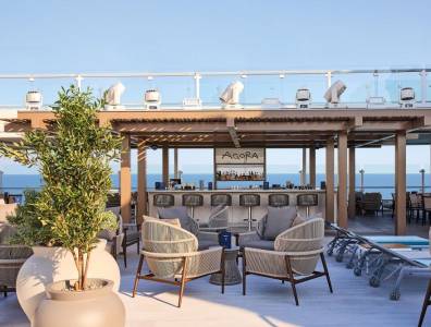 Stylische Außenbar „Agora“ mit Lounge-Möbeln auf dem Sonnendeck eines Kreuzfahrtschiffs mit Meerblick