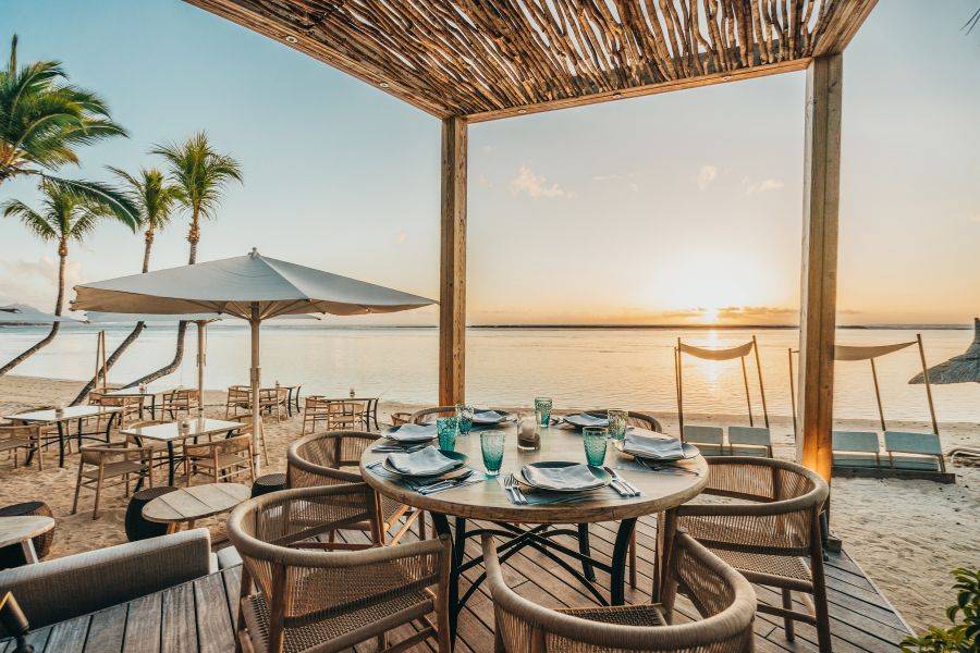 Blick auf den Restaurantbereich des Resorts. Man hat einene Ausblick auf das Meer und den Strand. Palmen machen den Anblick komplett.