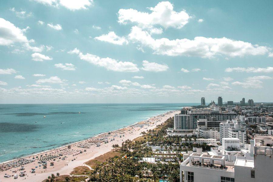 Panoramablick auf Miami Beach mit Skyline, Art-Déco-Hotels und langem Sandstrand – typisches Bild für einen Badeurlaub in Südflorida.