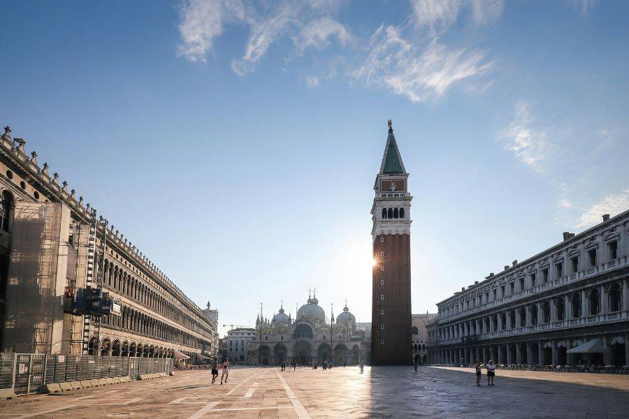 Weitwinkelaufnahme des Markusplatzes in Venedig mit dem Campanile und der Basilika im frühen Tageslicht.