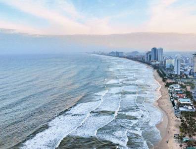 Luftaufnahme der Küstenlinie von Da Nang mit Wellen und Hochhäusern am Strand