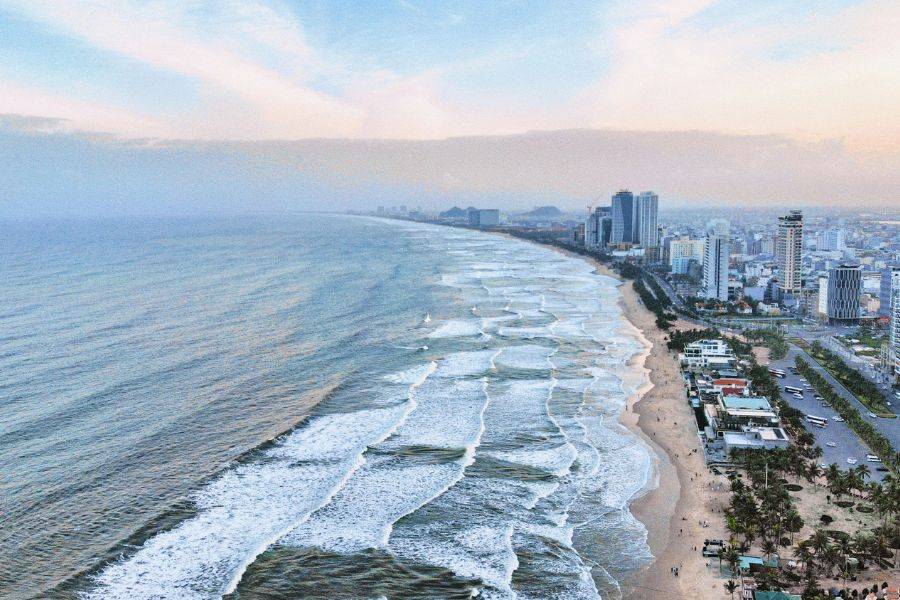 Luftaufnahme der Küstenlinie von Da Nang mit Wellen und Hochhäusern am Strand