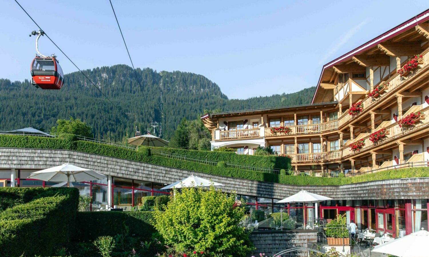 Außenansicht des Hotel Kaiserhof Kitzbühel mit Blick auf die Kitzbüheler Alpen und die Hahnenkamm-Bergbahn