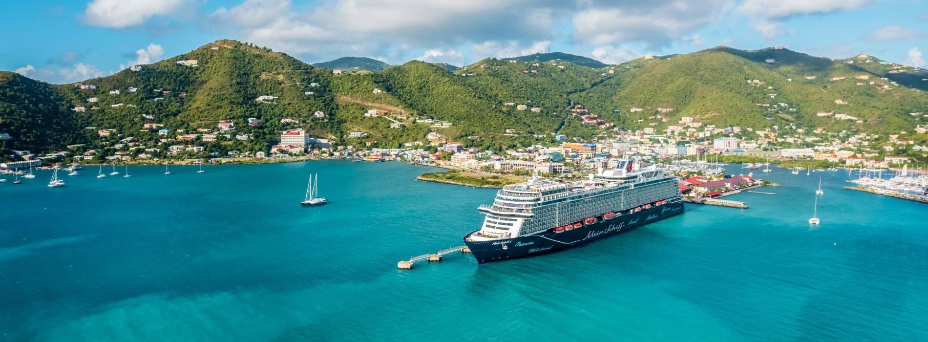 Kreuzfahrtschiff der Mein Schiff® Flotte im Hafen einer Karibikinsel