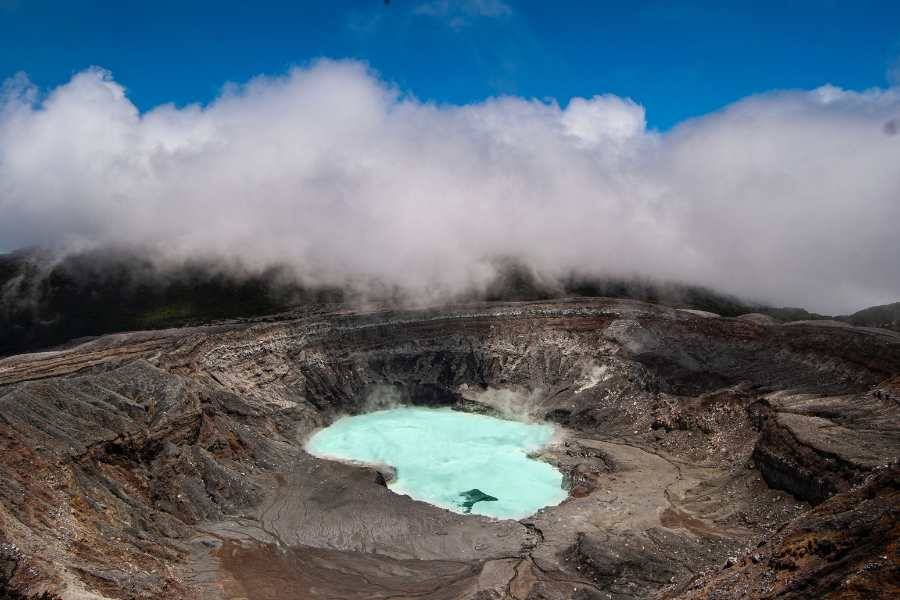 Krater eines Vulkans mit einem milchig-türkisen See und Nebel, wahrscheinlich der Poás-Vulkan in Costa Rica.