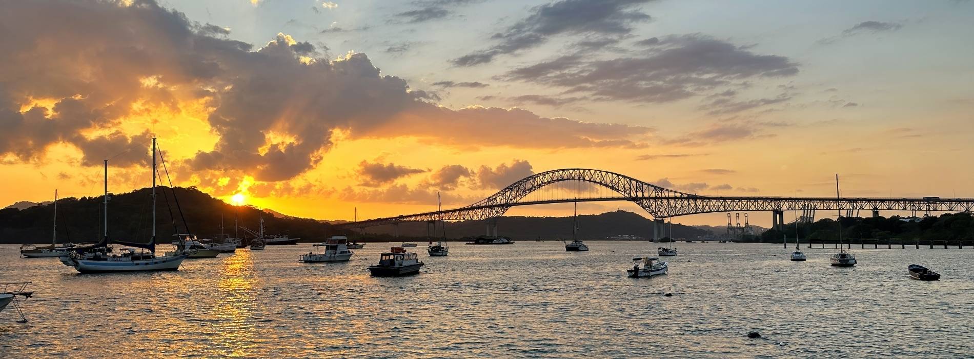 Sonnenuntergang über der Brücke des Panamakanals mit Segelbooten im Hafen