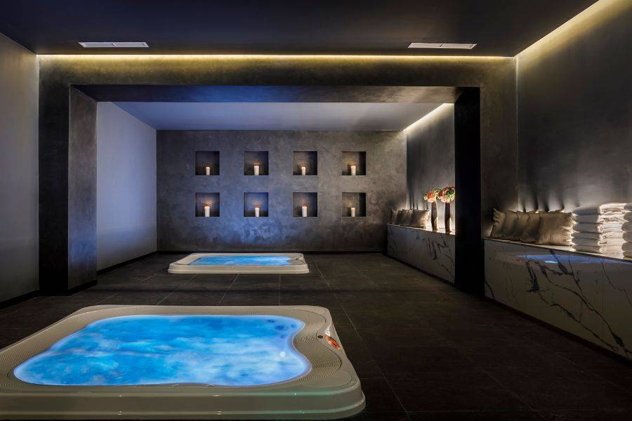 Moderner Wellnessbereich mit beheizten Liegen, weichen Handtüchern und einer beleuchteten Wand mit dekorativen Elementen, die eine entspannende Atmosphäre schaffen.