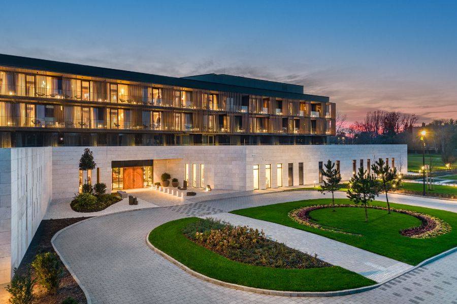 Eine elegante Hotelanlage mit beleuchteter Fassade und gepflegtem Garten in der Abenddämmerung.