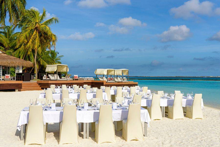 Festlich gedeckte Tische für eine Hochzeitsrezeption am Strand.