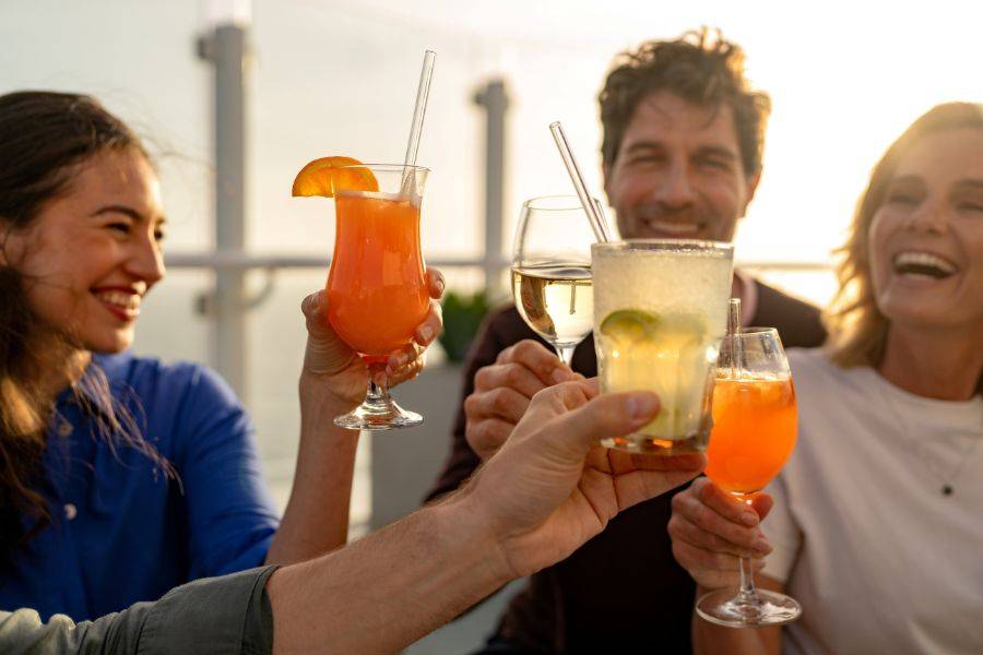 Gäste stoßen mit Wein und Cocktails an Bord eines Mein Schiff Kreuzfahrtschiffs an 