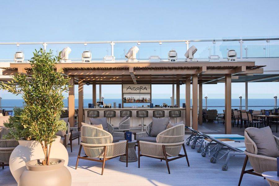 Stylische Außenbar „Agora“ mit Lounge-Möbeln auf dem Sonnendeck eines Kreuzfahrtschiffs mit Meerblick