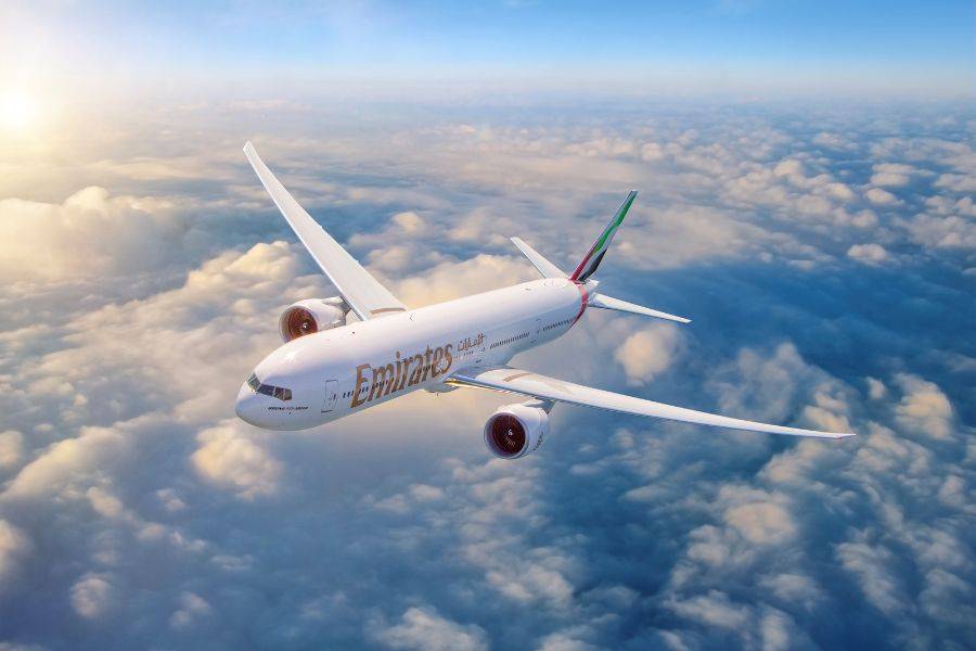 © Emirates Passagierflugzeug der Fluggesellschaft Emirates fliegt bei Sonnenaufgang über eine geschlossene Wolkendecke