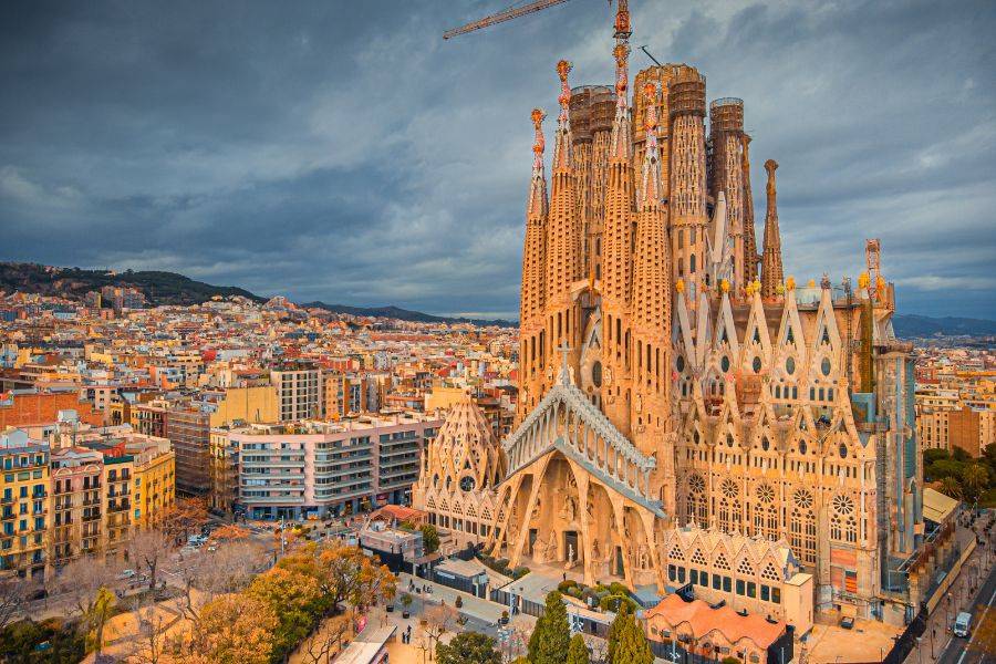 Sagrada Família bei dramatischem Himmel – Die beeindruckende Basilika von Antoni Gaudí erhebt sich majestätisch über Barcelona, umgeben von der Stadtlandschaft. Die dunklen Wolken verstärken die Atmosphäre dieses architektonischen Meisterwerks.