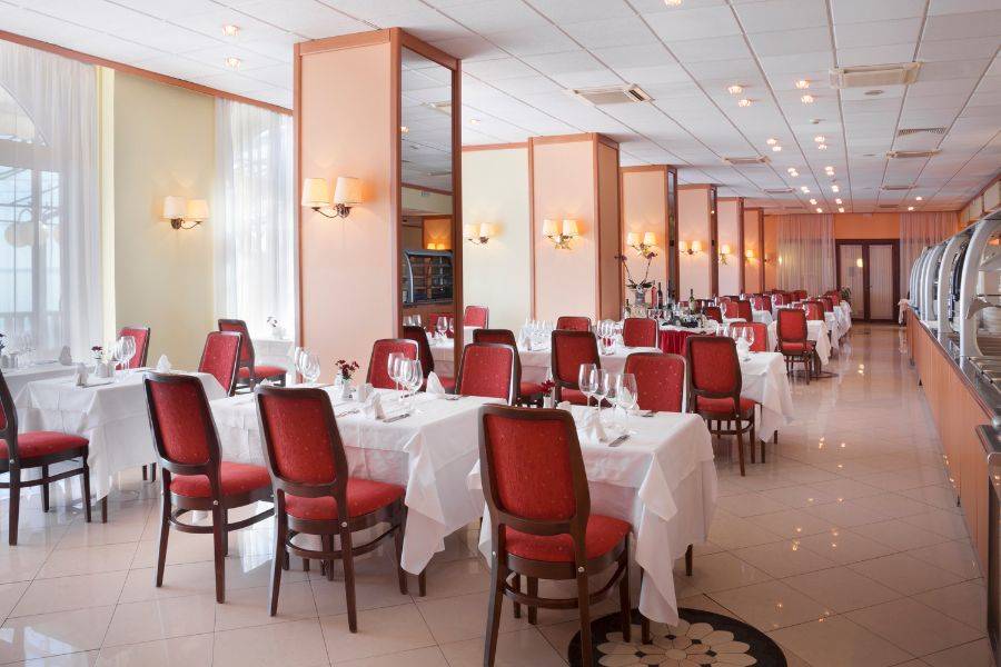 Das helle Restaurant mit roten Stühlen und gedeckten Tischen.