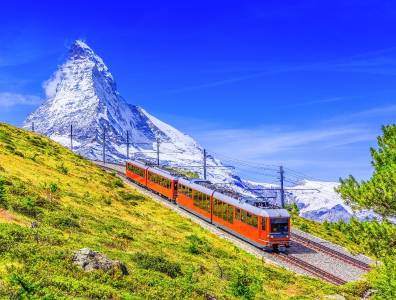 Roter Panoramazug fährt durch die Schweizer Alpen mit Blick auf das Matterhorn bei klarem Himmel