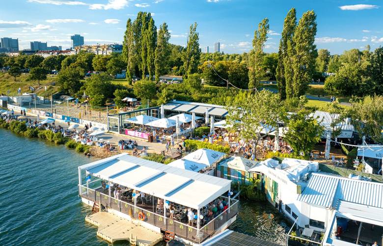 Luftaufnahme des Vienna City Beach Club mit Strand, Volleyballfeldern und Lounges am Wasser