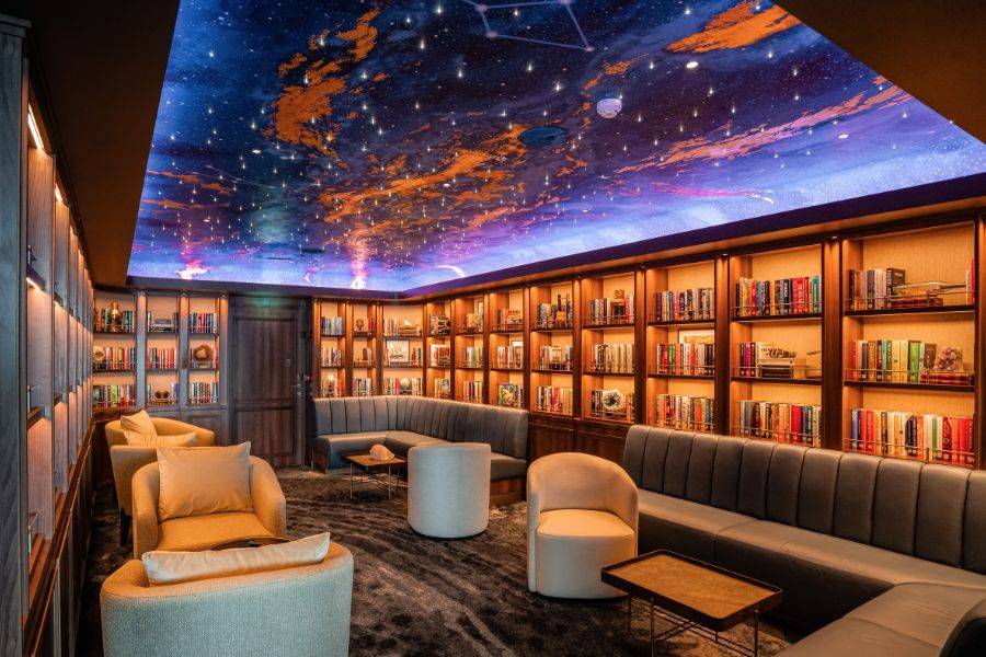 Elegante Lounge mit Bücherregalen und kunstvoll gestaltetem Sternenhimmel