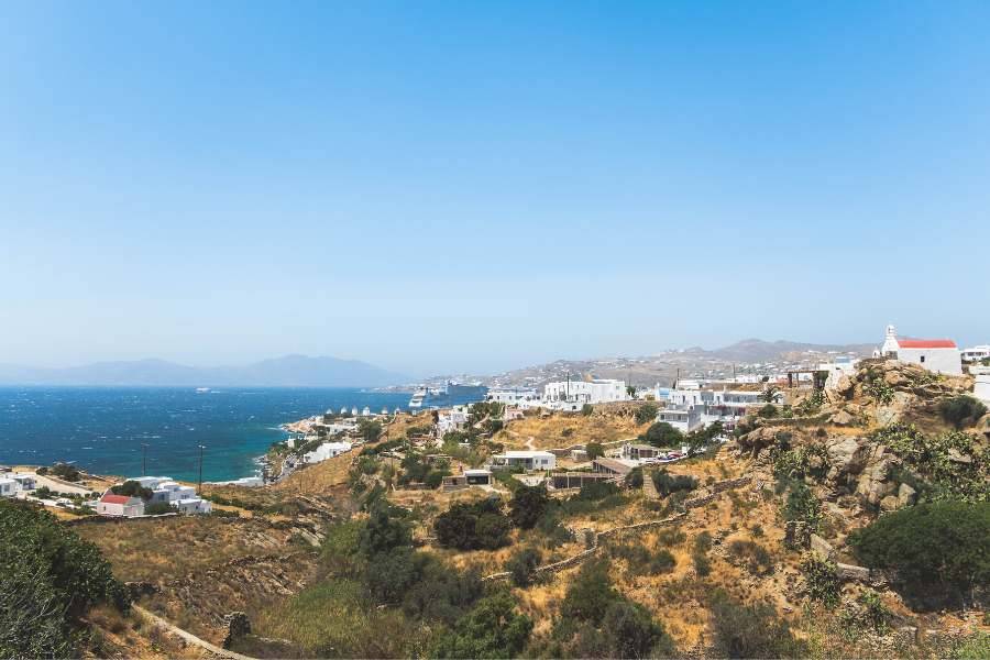 Panoramaausblick über eine Küstenlandschaft mit blauem Meer und weißen Häusern auf den Hügeln.