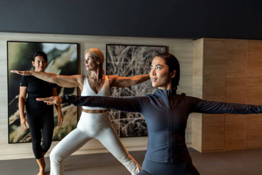 Eine Gruppe von Frauen in einem stilvollen Studio praktiziert Yoga, konzentriert und in harmonischer Bewegung.