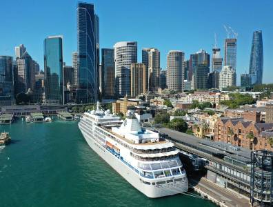 Ein großes Kreuzfahrtschiff liegt am Hafen einer modernen Stadt mit einer beeindruckenden Skyline aus Wolkenkratzern