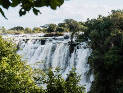 Blick auf die imposanten Victoriafälle in Simbabwe, umgeben von üppiger tropischer Vegetation.