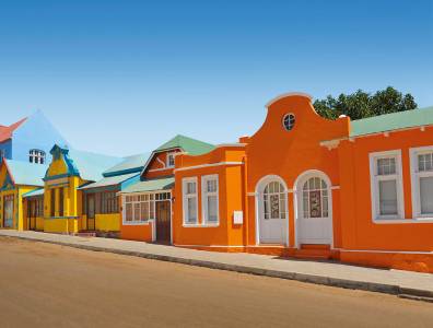 Farbenfrohe Kolonialhäuser in einer Küstenstadt mit pastellfarbenen Fassaden unter blauem Himmel