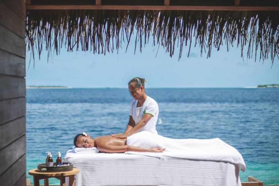 Entspannende Spa-Behandlung mit Blick auf das Meer, unter einem offenen, strohgedeckten Pavillon.