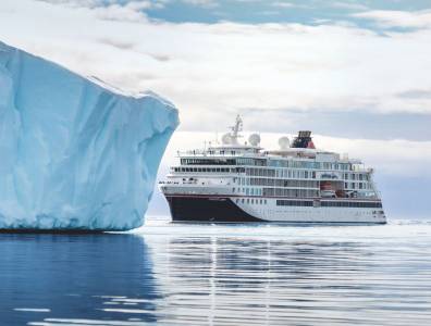 Expeditionsschiff von Hapag-Lloyd Cruises fährt an einem großen Eisberg in polaren Gewässern vorbei