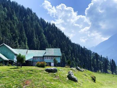 Traditionelles Ferienhaus in den Bergen, umgeben von Wiesen und dichtem Wald