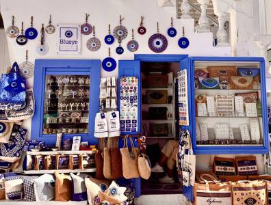 Traditioneller Souvenirladen in Mykonos mit Nazar-Amuletten, handgefertigten Taschen und buntem Schmuck im typischen Blau-Weiß.