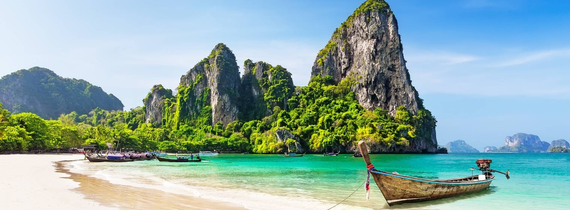 Longtail-Boot an Strand mit Felsen in Thailand
