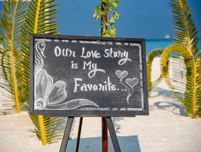 Hochzeitsdekoration am Strand der Malediven mit Schild „Our Love Story is my Favorite“.