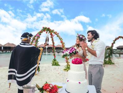 Eine Strandzeremonie mit geschmückten Hochzeitsbogen und einer Hochzeitstorte.