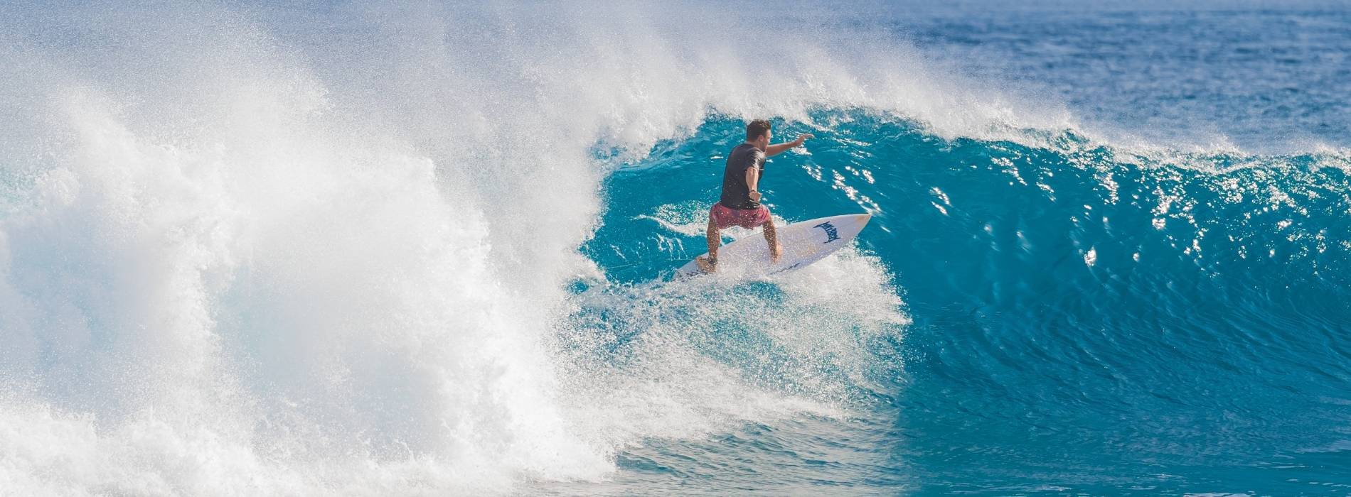 Surfer reitet eine große Welle im offenen Meer bei strahlendem Wetter