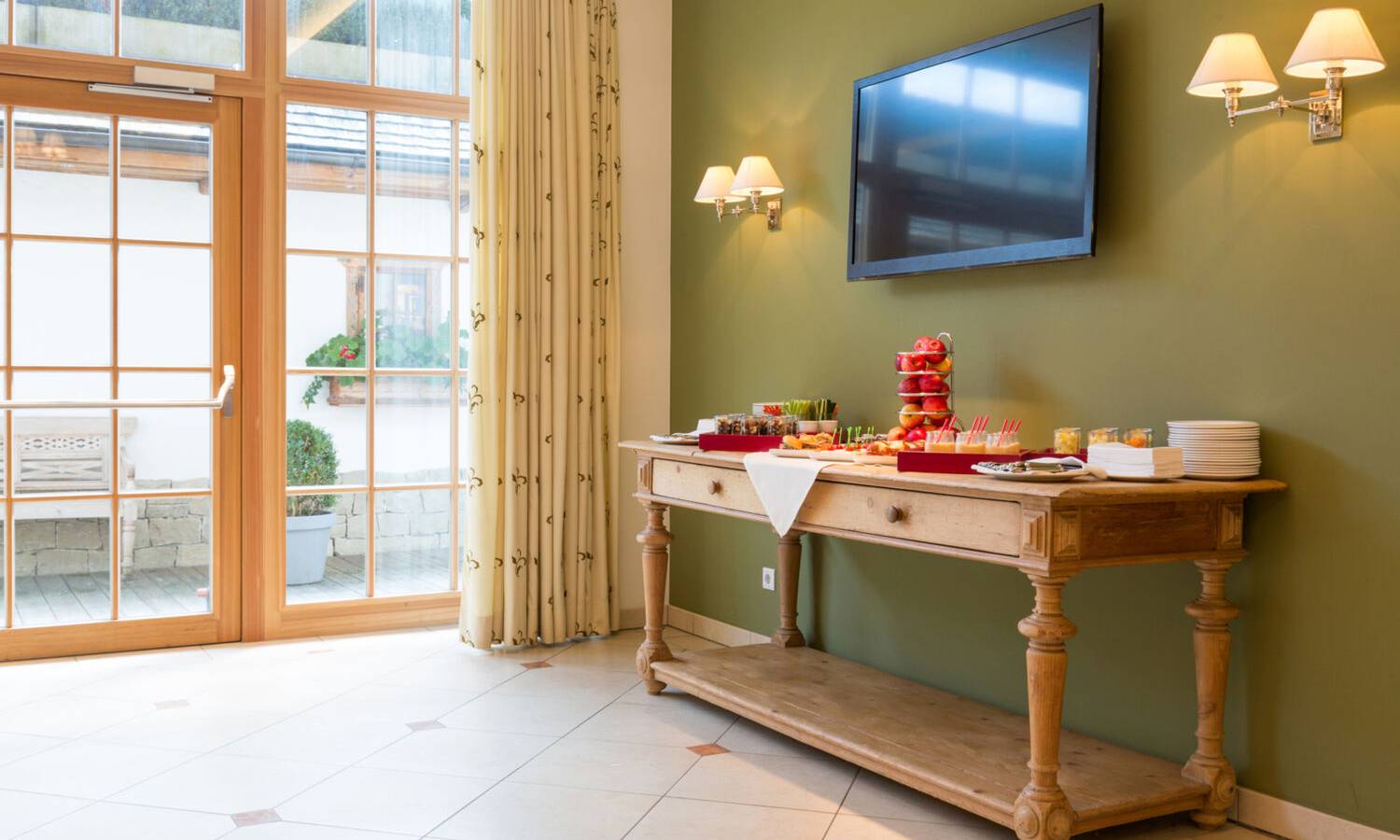 Meetingbereich im Hotel Kaiserhof Kitzbühel mit Lounge-Sitzbereich, Kaffeepause-Buffet und Präsentationsbildschirm