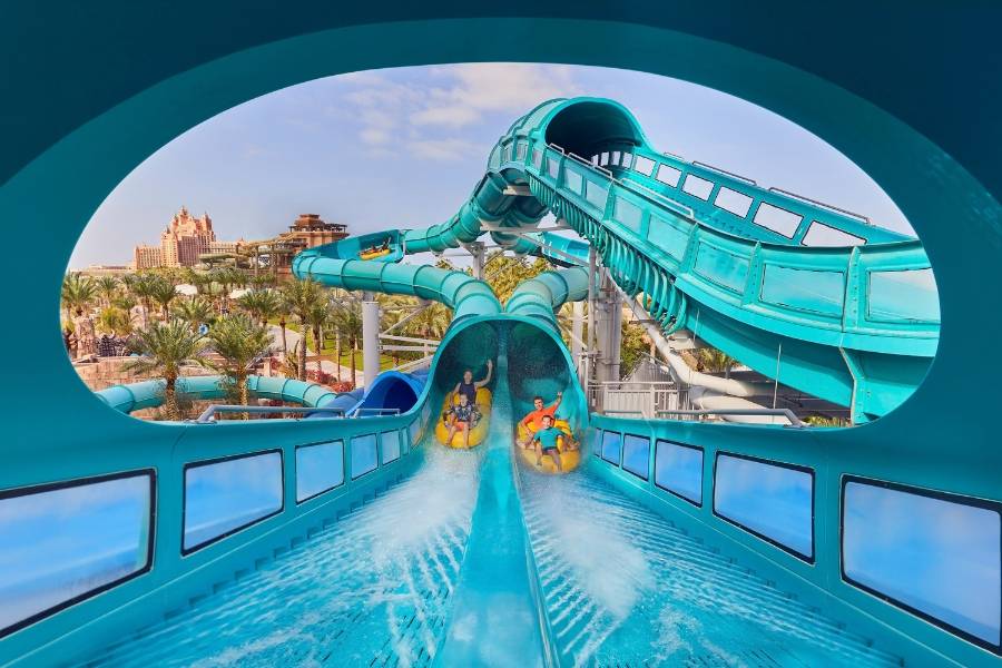 Gäste auf einer türkisfarbenen Wasserrutsche in der Aquaventure World in Dubai