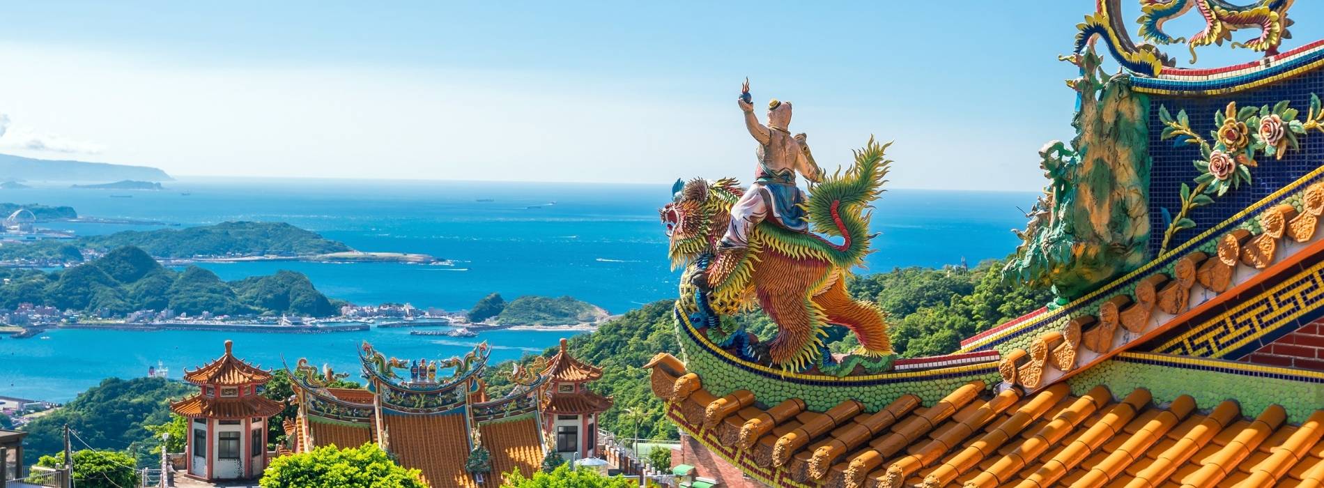 Verzierte Tempeldächer mit Drachenfiguren und Blick auf Küste und Meer in Taiwan