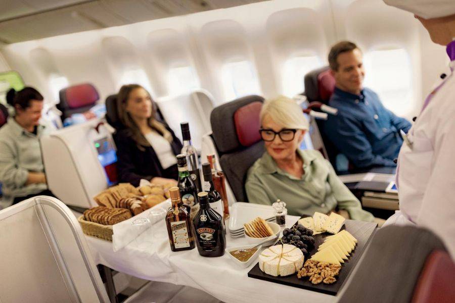 Neben einer Passagierin in der Business-Class sieht man einen gedeckten Essenswagen.
