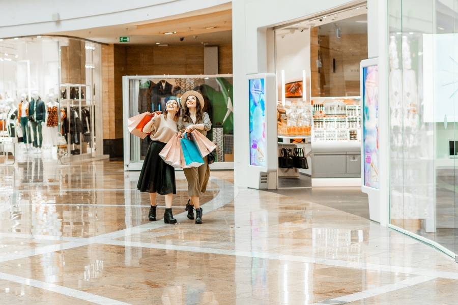 Zwei Frauen mit Einkaufstaschen beim Shopping in einem modernen Einkaufszentrum in Dubai