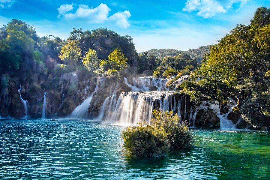 Mehrstufige Wasserfälle in einer grünen Naturlandschaft mit klarem Wasser und dichtem Wald