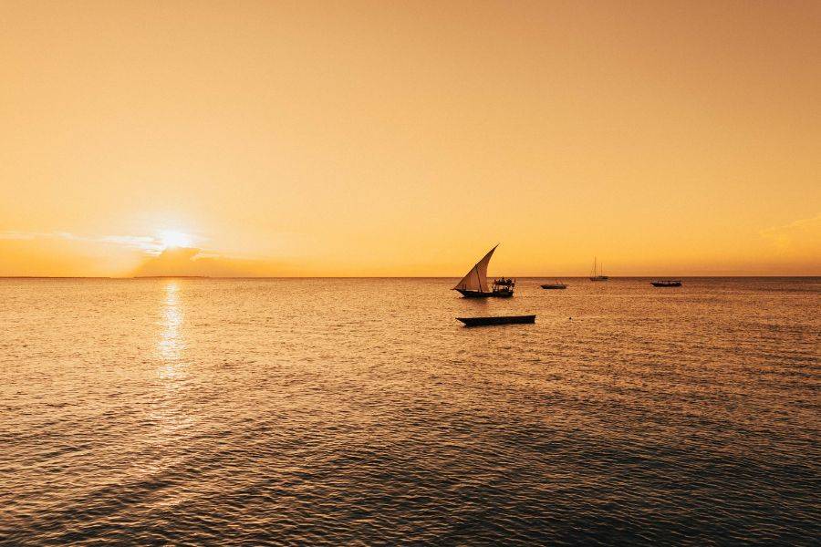 Ein einsames Boot auf dem Meer. im Hintergrund sieht man den Sonnenuntergang.