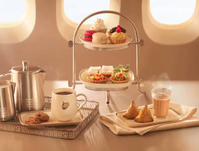 Indischer Afternoon-Tea an Bord von Air India mit Tee, Samosas, süßen Gebäckstücken und Macarons, serviert auf edlem Tablett.