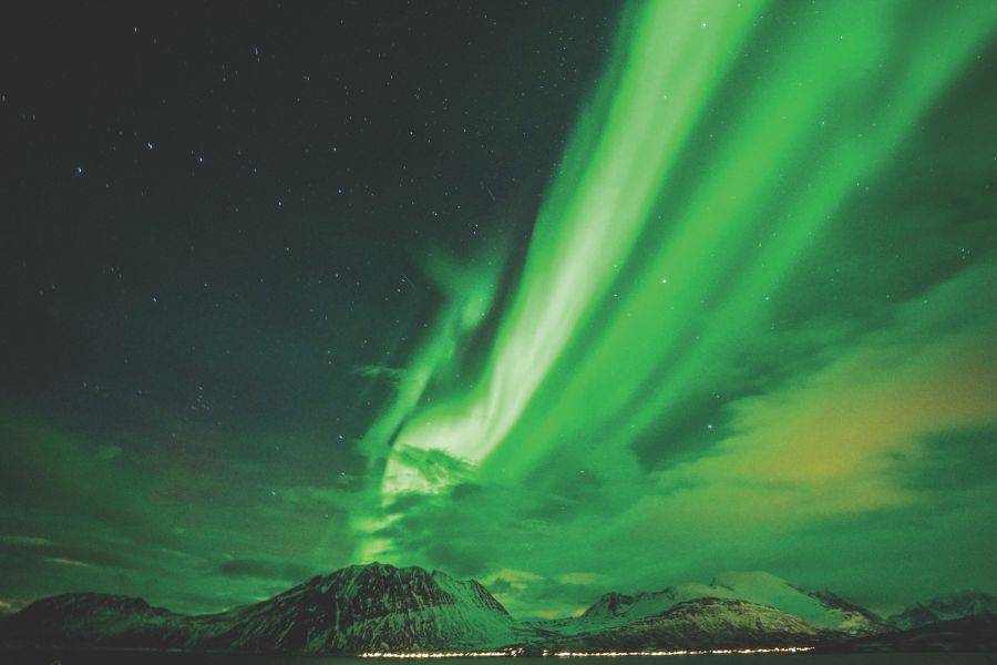 Nordlichter über verschneiten Bergen in Norwegen bei Nacht