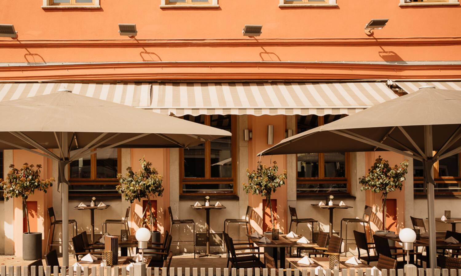Außenterasse im Hotel Raffel mit Sonnenschirmen und Sirzplätzen im Freisen für Afterworks, Bruch und Kaffeeepausen