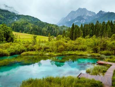 Berglandschaft im Triglav-Nationalpark mit klarem See, Wiesen und Alpenpanorama in Slowenien