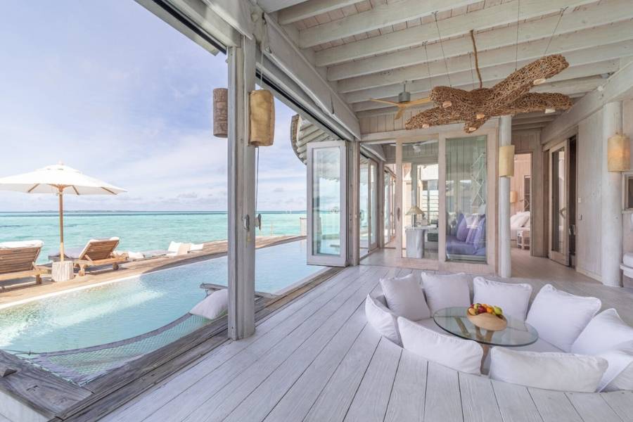 Offener Wohnbereich einer Soneva Jani-Wasservilla mit versenkter Sitzecke, privatem Pool und Blick auf die Lagune