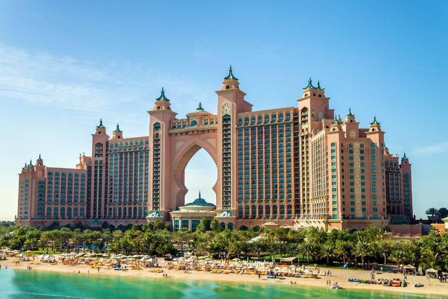 Außenansicht des imposanten Atlantis The Palm Resorts in Dubai, mit markanter Architektur, türkisfarbenem Wasser und weißem Sandstrand im Vordergrund.