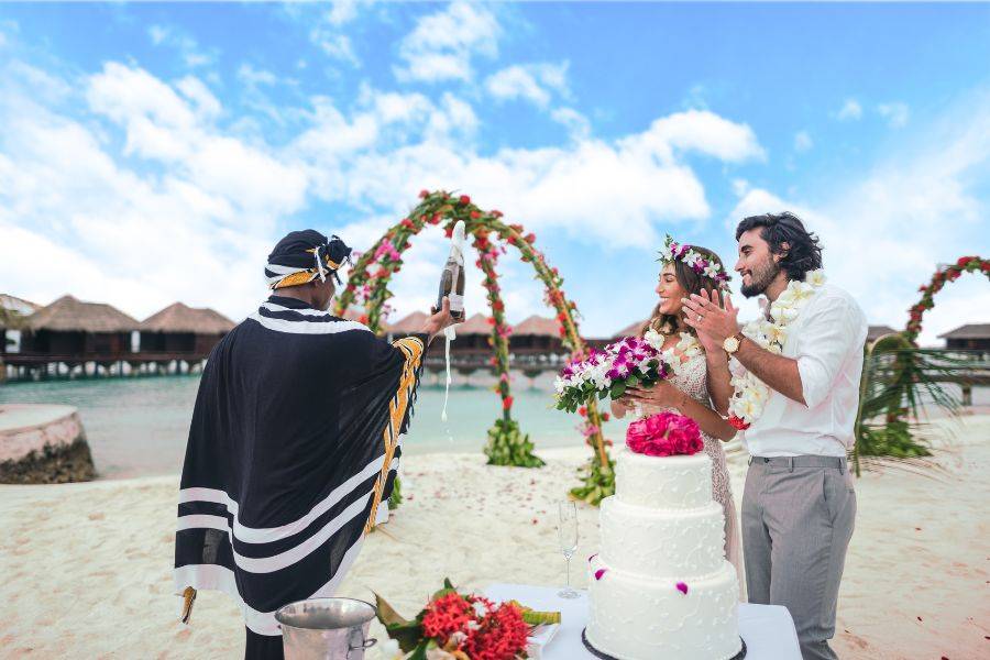 Eine Strandzeremonie mit geschmückten Hochzeitsbogen und einer Hochzeitstorte.